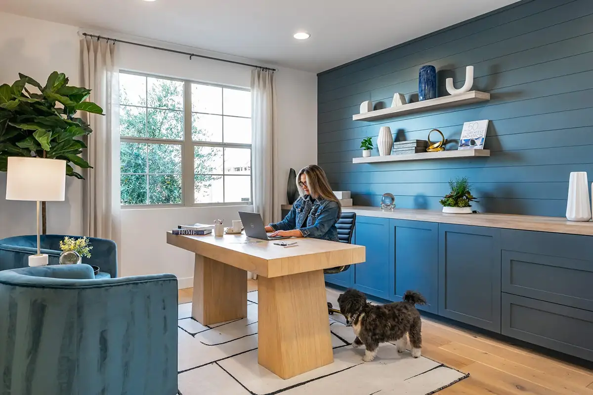Woman sitting at home office working on computer with dog at her feet